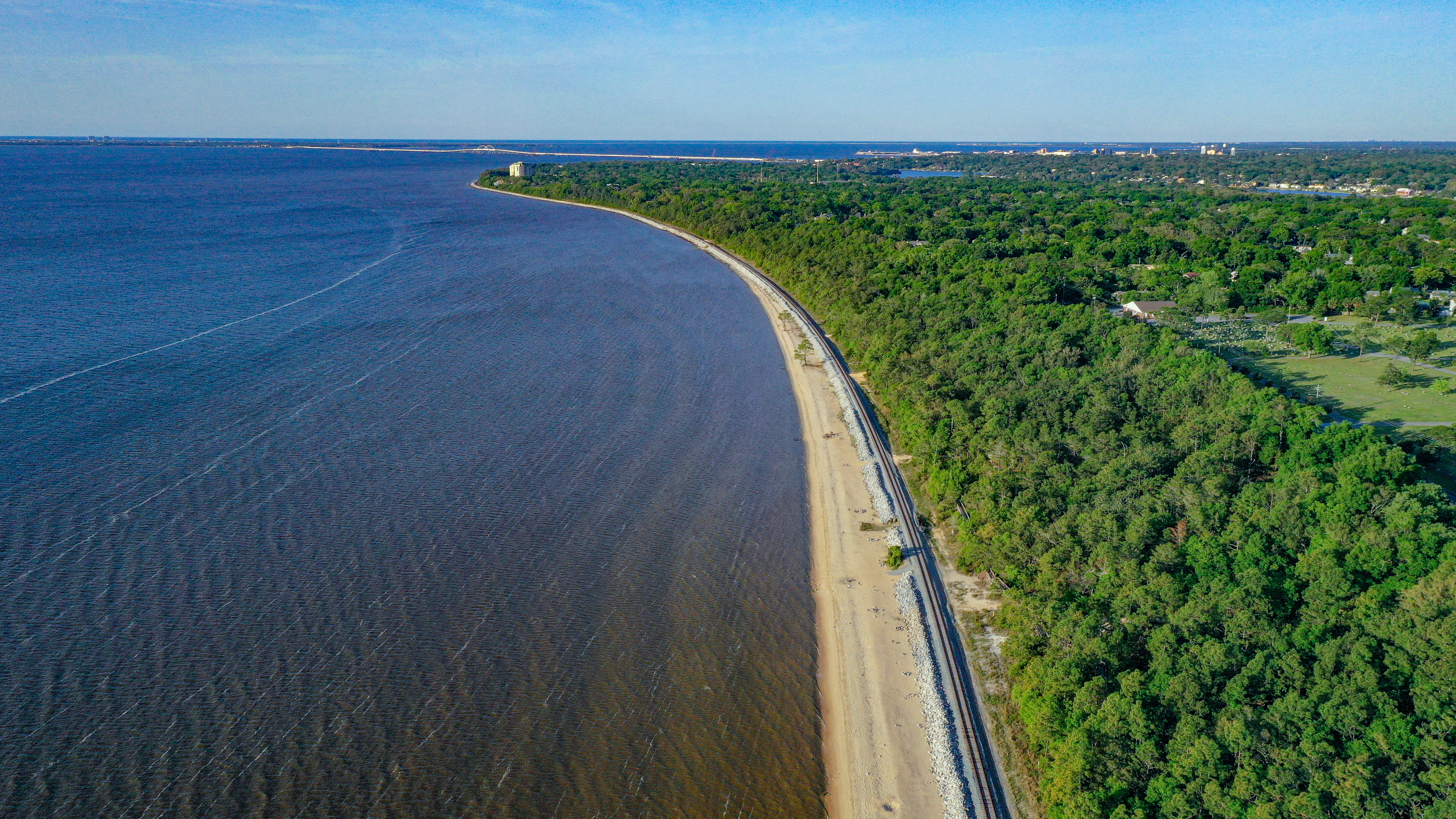 Aerial view of Pensacola Bay bluffs showing the coastline, railroad, and forested neighborhoods